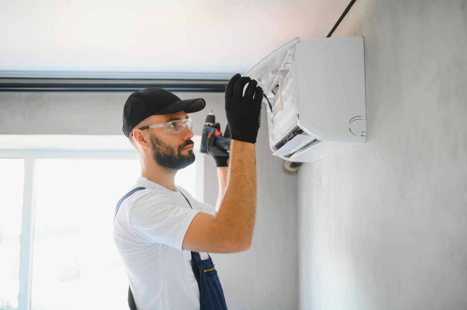 HVAC technician inspecting and servicing a wall-mounted air conditioning unit in a residential setting.